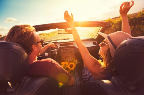 Happy Young Couple Driving Along Country Road in Convertable at Sunset. Freedom Adevnture Roadtrip!